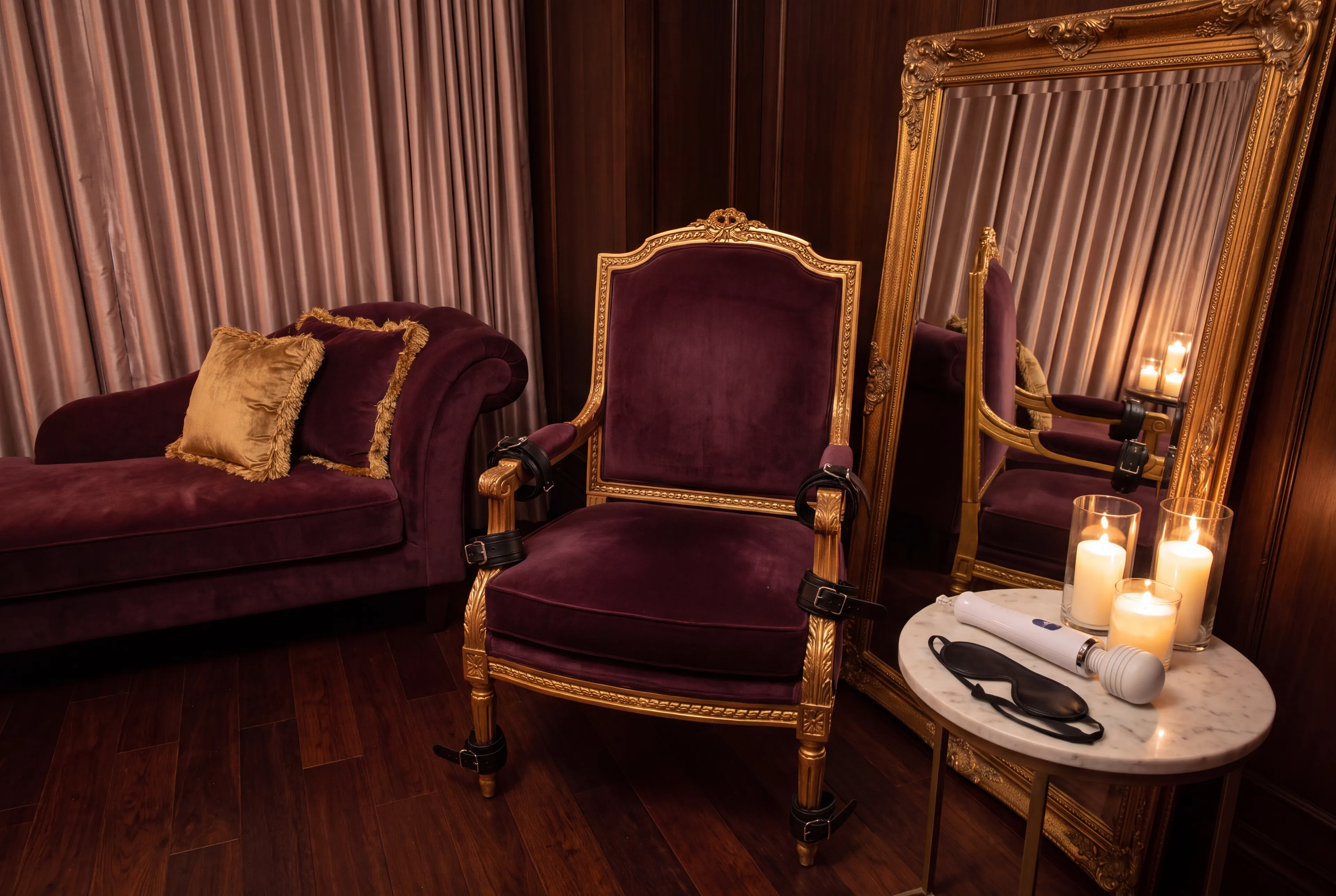 A tall plum velvet throne chair with leather cuffs on the armrests in a plum and gold boudoir lit by candles